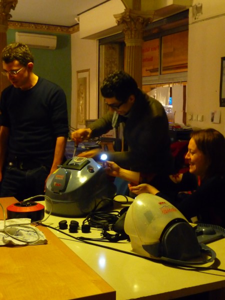 Le propriétaire de la centrale vapeur ouvre cette dernière et sa compagne l'éclaire avec une lampe pour que le réparateur puisse regarder dedans.